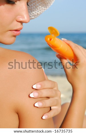 Woman applying suntan lotion on shoulder