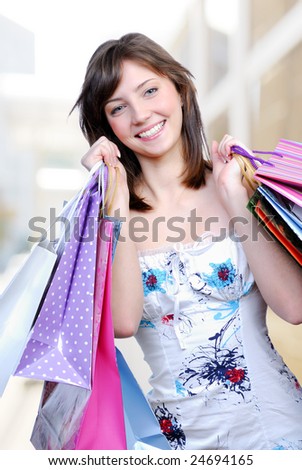 Young adult beautiful girl holding colored bags with purchase