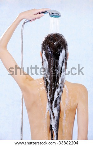 Young female with douche standing back with stream water on head