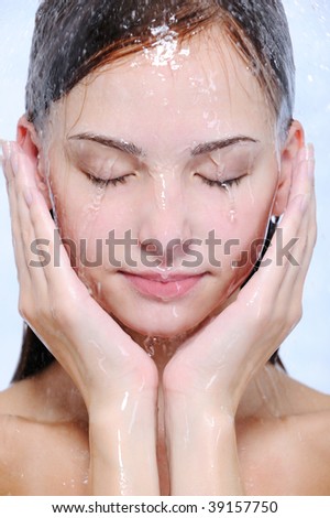 Streams of water on the young beautiful female face - close-up