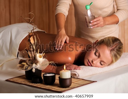 professional masseur applying massage oil on female back in the beauty salon