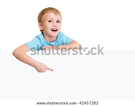 Cute laughing little boy is above on a white blank poster and points on it.