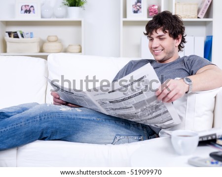 Happy smiling handsome man reading newspaper at home