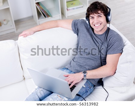 High angle portrait of smiling young handsome guy with laptop using headset