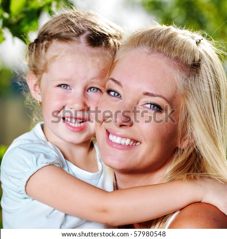 Happy faces of the young  mother and  little girl outdoor