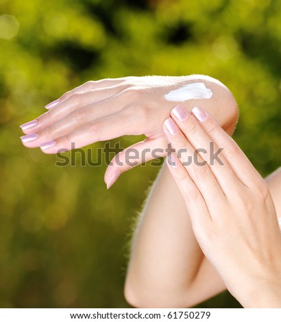 Closeup photo of a beautiful female hand with cosmetic cream on it. Green natural background