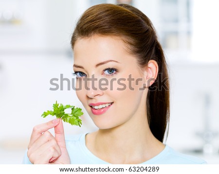Young woman with green fennel in hand - on kitchen