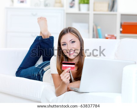 happy young beautiful woman holding credit card and using laptop - indoors