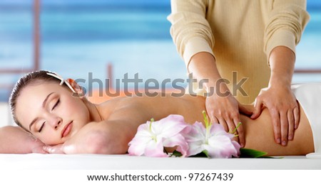 Young woman  relaxing in spa salon and getting massage of body