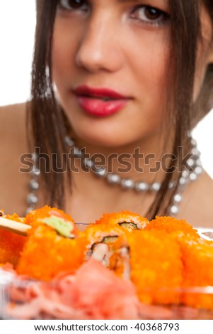 Beautiful young woman eating sushi california roll . Shallow depth of field, focus is on the sushi. isolated, studio.