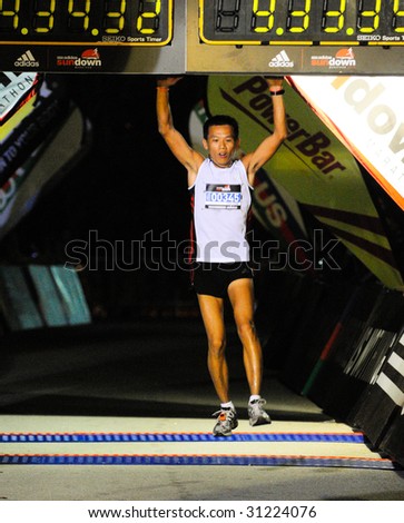 SINGAPORE - 31 May: Ultra marathoner finisher leaping to touch timer boards at the finish at the Adidas Sundown Marathon held in Singapore on 30 and 31 May 2009.