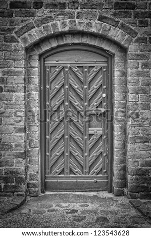 A black and white photo of an arched doorway to a church.