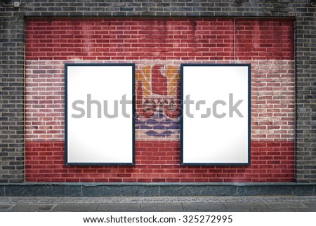 Two blank billboards attached to a buildings exterior brick wall which has a French Polynesia flag painted on it.