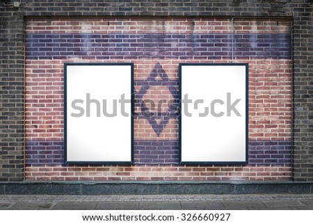 Two blank billboards attached to a buildings exterior brick wall which has a Israel flag painted on it.