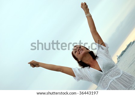 A beautiful, fit and healthy young woman throws her hands in the air in a fit of joy.