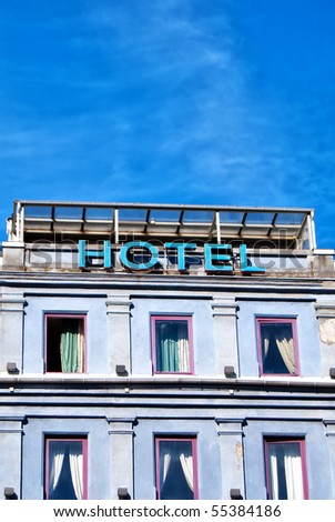An unlit neon hotel sign situated next to the room windows