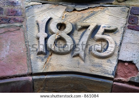 A sandstone key-stone in a building arch showing the construction date of 1875.