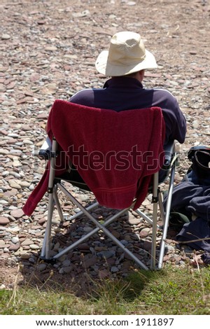 A middle-aged man at the seaside in the sun. Sitting back and enjoying the warmth whilst taking things easy.