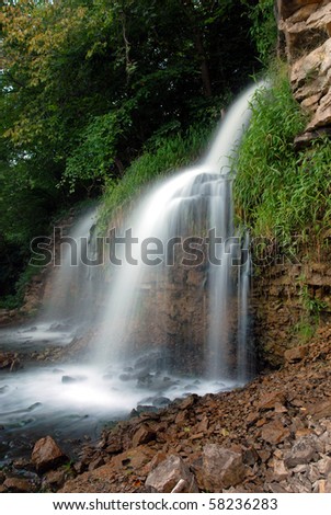 A colorful image of a fast flowing waterfall photographed using a slow shutter speed for artistic effect.