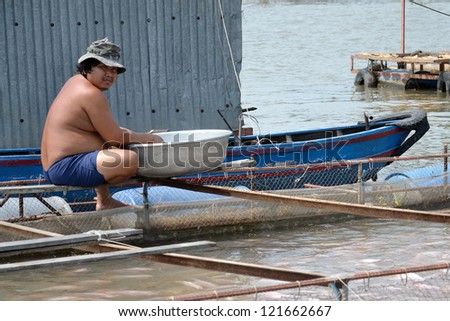 MY THO, VIETNAM - FEBRUARY 14: Fisherman on cage with fish on February 14, 2012 in My Tho, Vietnam. Government will set up forces to protect vietnamese fisheries on sea for early next year.