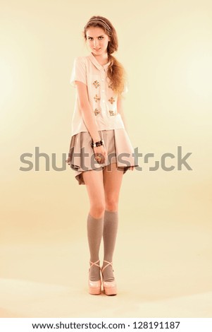 Fashion model posing in pastel clothes on beige background.