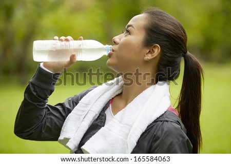Asian woman drinking water after fitness exercise in the garden