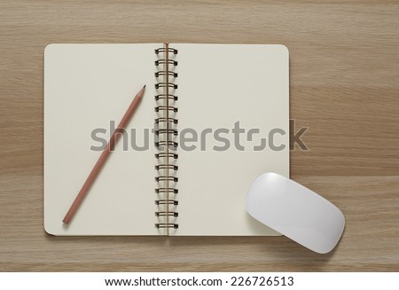 Blank Spiral Note Pad, computer mouse and Pencil on Wood Background.