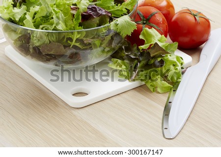 Fresh vegetables and salad ingredients on a wooden kitchen table.
