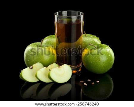Four whole green apples, three parts of an apple and juice glass