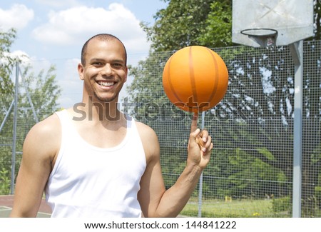 Portrait of a MIxed race basketball Player Spinning the Ball on an outdoor basketball court