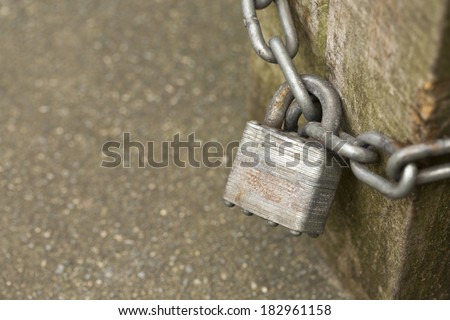 Locked padlock and chain on a wooden bench leg with copy space. Shallow depth of field