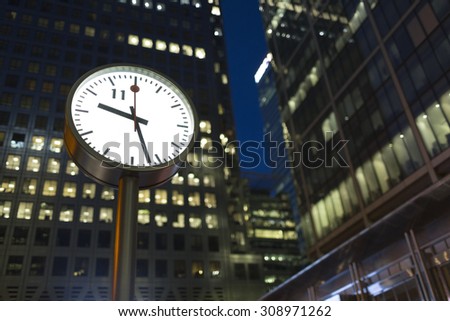 LONDON, UK - AUGUST 3, 2015 - Canary Wharf clock in the evening as office lights remain on in the background. Central finance district in London