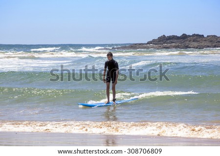 young teen boy learning how to surf waves