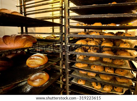 Racks of fresh buns with olives and bread from oven in Bakery