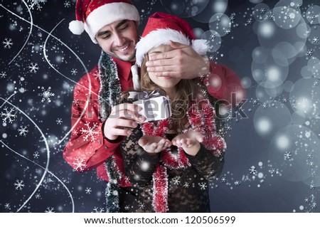 Boy give a Christmas gift to her girlfriend. Happy young couple wearing Santa hat.Magic card.