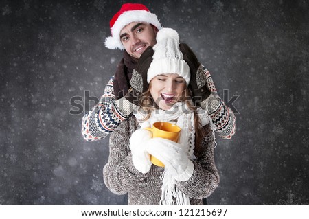 Happy funny couple  with a cup of tea covering  snow background. 	 Have a warm. Fool around.