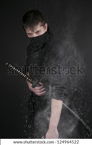 Ninja - spy, saboteur, stealth assassin of feudal Japan. Ninja with sword in a spray of flour.