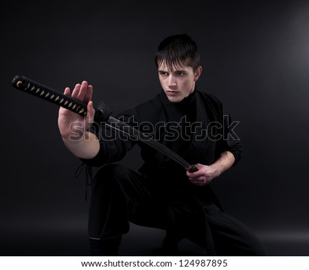 Ninja - spy, saboteur, stealth assassin of feudal Japan. Ninja with sword over dark background.