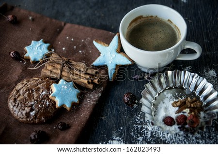 Christmas homemade chocolate chip cookies, cup of coffee and cinnamon sticks on a wooden background.