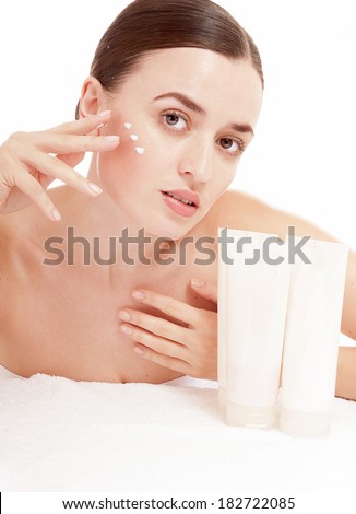 Woman applying moisturizer cream on face. Skin care concept.