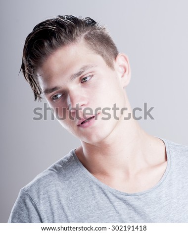 Handsome young man with fashion hairstyle over gray background.