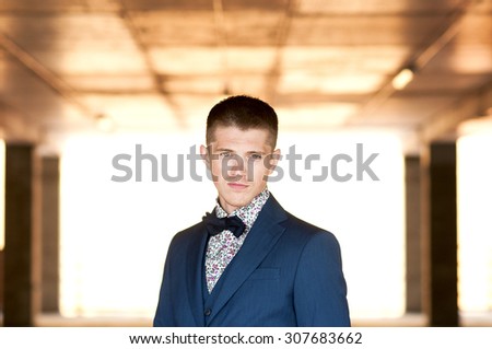 Frontal portrait of a young attractive man in blue suit with bow tie.