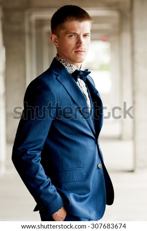 Handsome elegant man wears blue suit with bow tie outdoor.