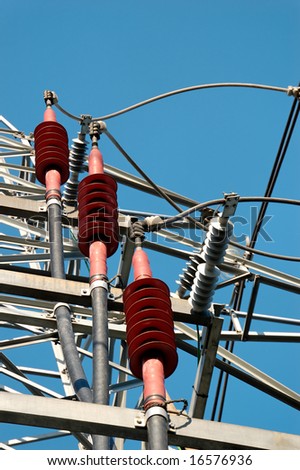 Three red ceramic high-voltage power line fixtures for grounding of the cables