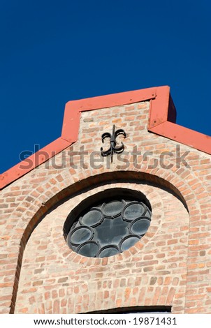 Rose window and a cast iron fixture of a brick factory house on polarised deep blue sky.