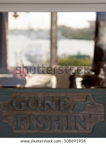 A generic sign that reads Gone Fishing placed in the window of a home.