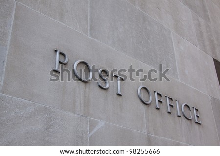 Metal letters that spell post office fastened to the side of a building.