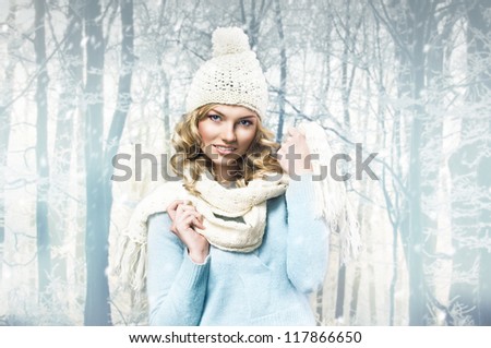 beautiful blonde woman wearing a wool winter cap and a scarf, blue woolen sweater against winter snowing scenery