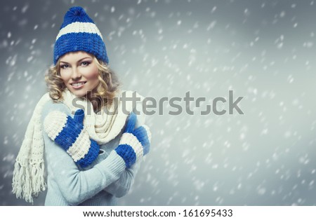 fashion picture of beautiful smiling blonde woman wearing a blue woolen sweater, a scarf and knitted cap