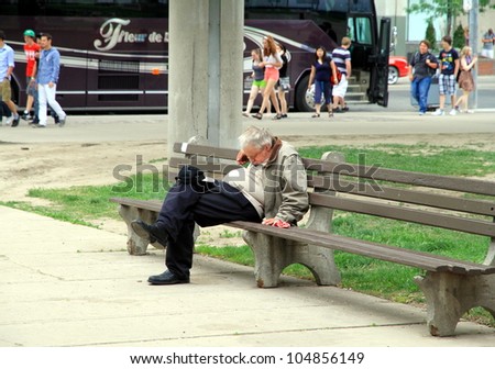 TORONTO - MAY 27: A man sleeps on a bench on May 27, 2012 in Toronto. Costs of homelessness in Canada in 2007 was between $4.5 to $6 billion in emergency services and community organizations.